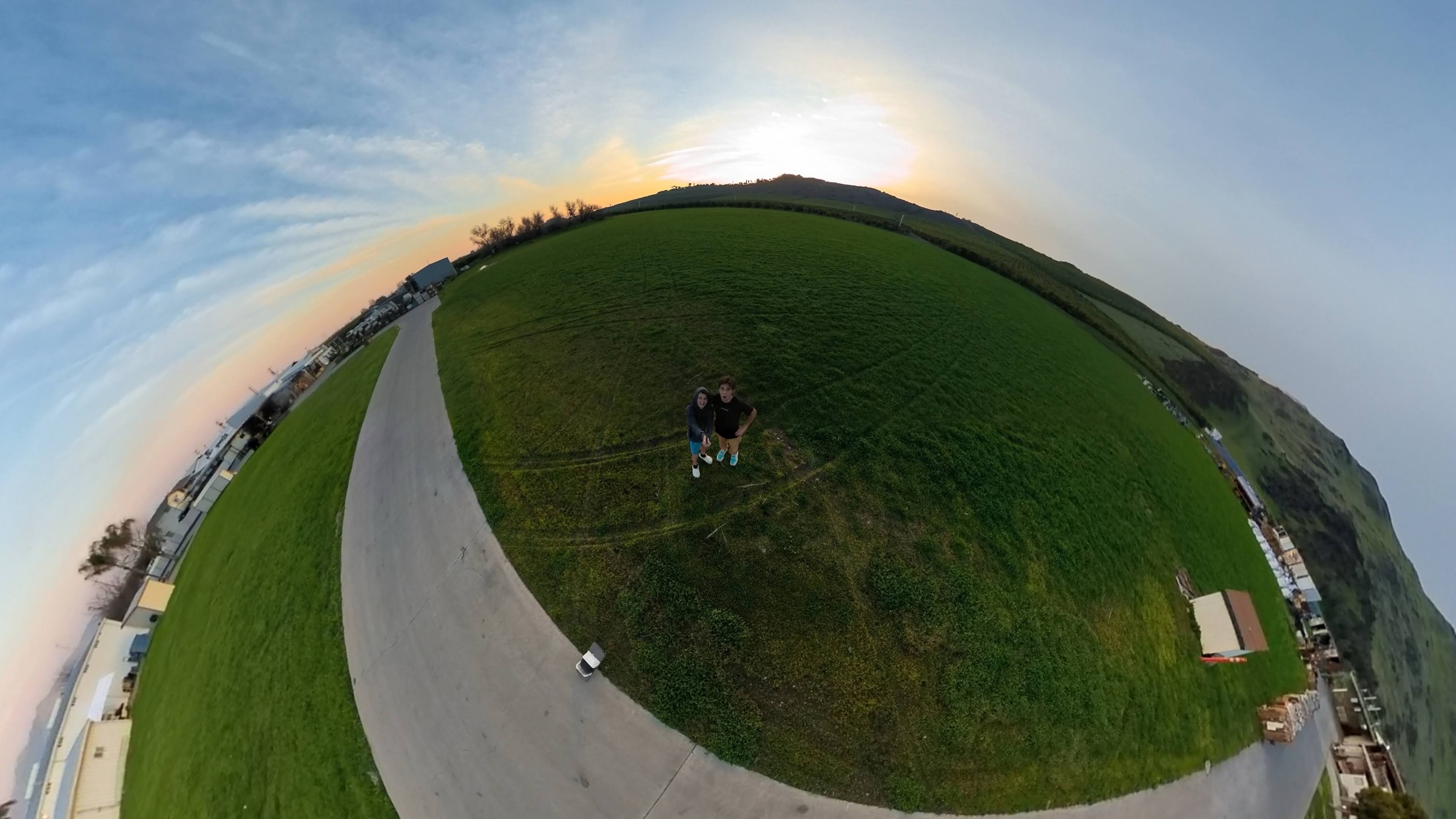 Tiny-planet 360 capture of a field and roadway curved into a sphere at sunset